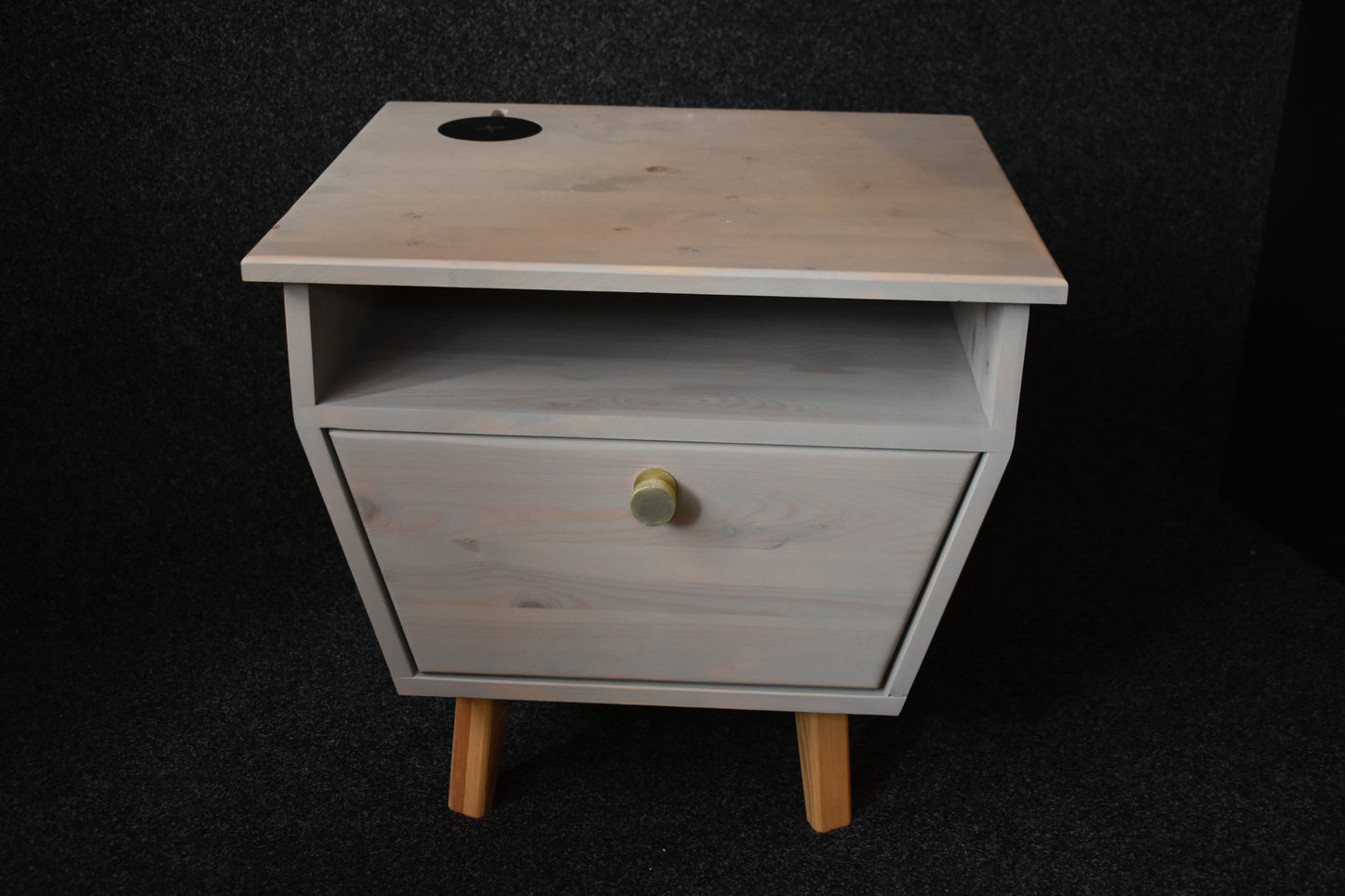 Funktionellt sängbord i ädelträ med integrerad trådlös laddare på ovansidan för en modern livsstil.