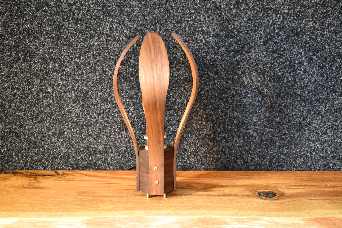 Bordslampa i ädelträ monterad med mässingsdetaljer för en stämningsfull och varm belysning.