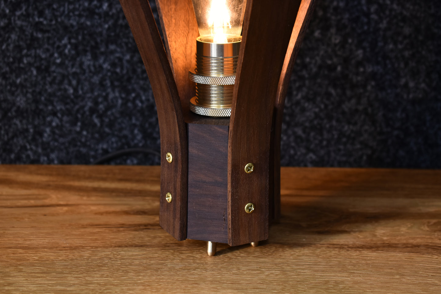 Närbild på det fina hantverket och den vackra ådringen i valnötsträet på bordslampan Droppen.