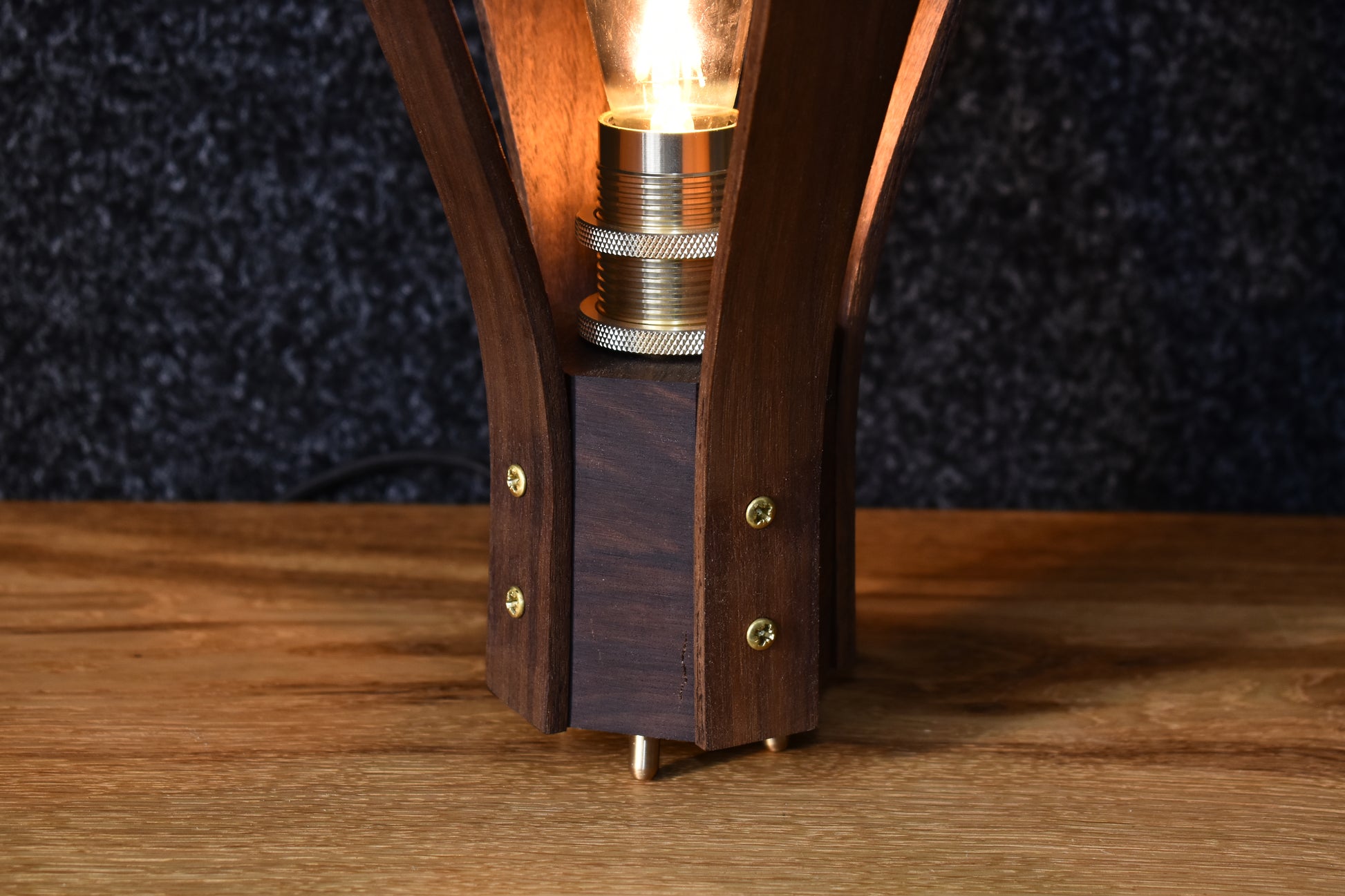 Närbild på det fina hantverket och den vackra ådringen i valnötsträet på bordslampan Droppen.