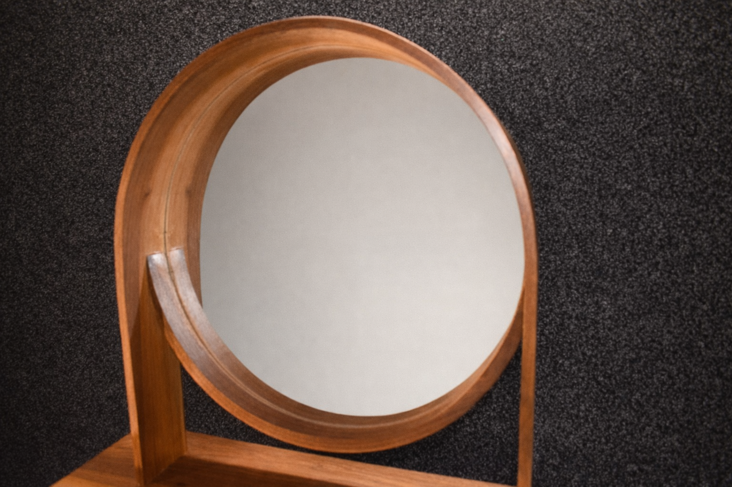 Närbild på den runda spegeln och den spektakulära ådringen i det massiva valnötsträet på ett sminkbord.