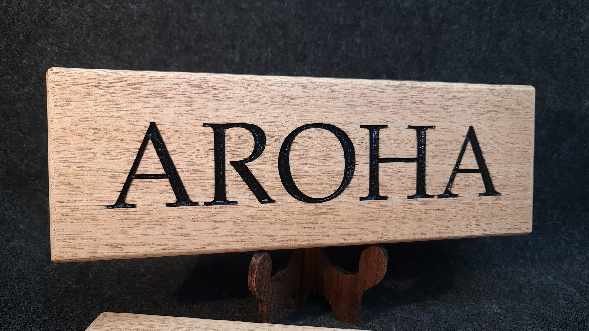 Personligt anpassad båtskylt i ädelträ mahogny med elegant relieftext, tillverkad för att tåla marin miljö.